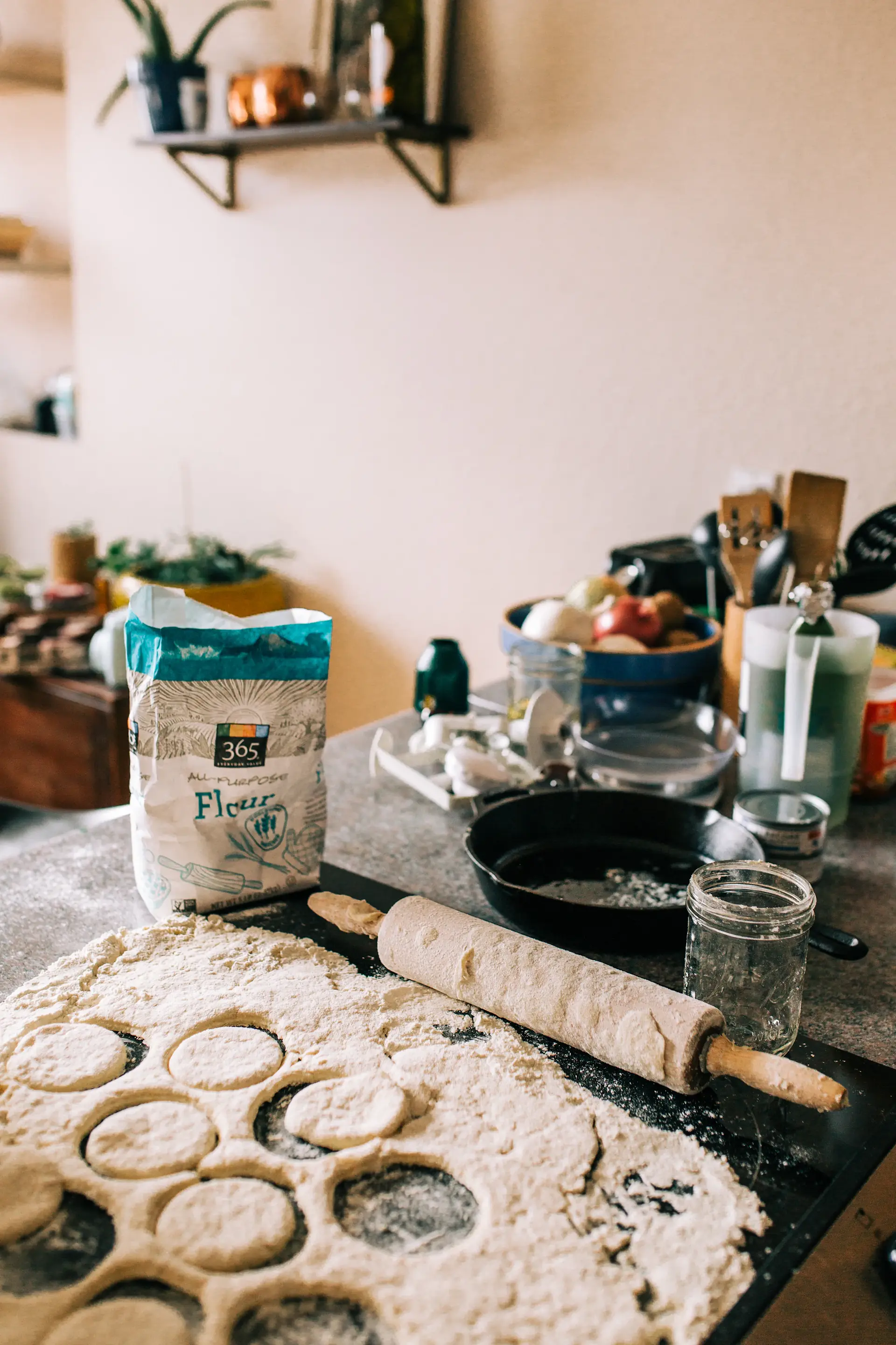 A home kitchen counter with flour, a rolling pin and cut dough