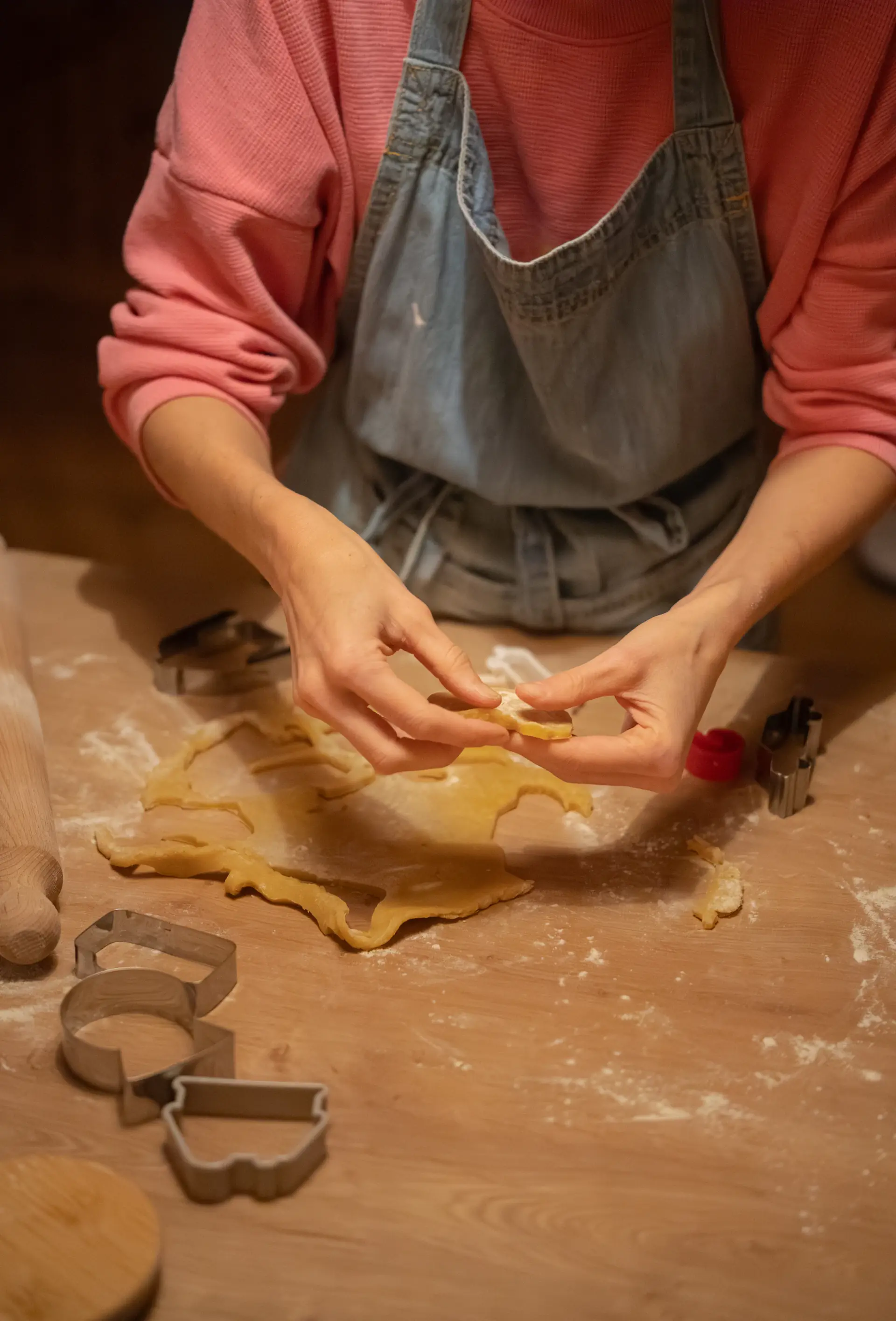 Hands cutting rolled cookie dough with cutters