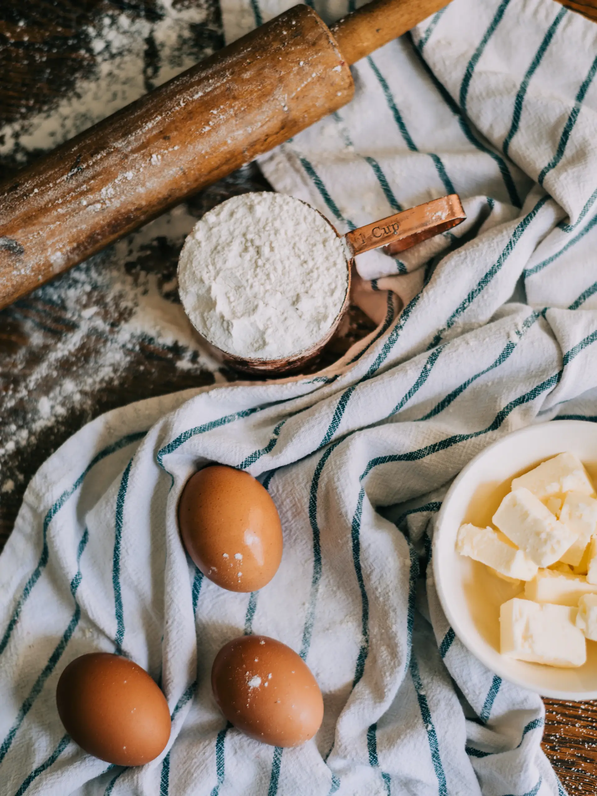Flour, eggs and butter on a striped kitchen towel