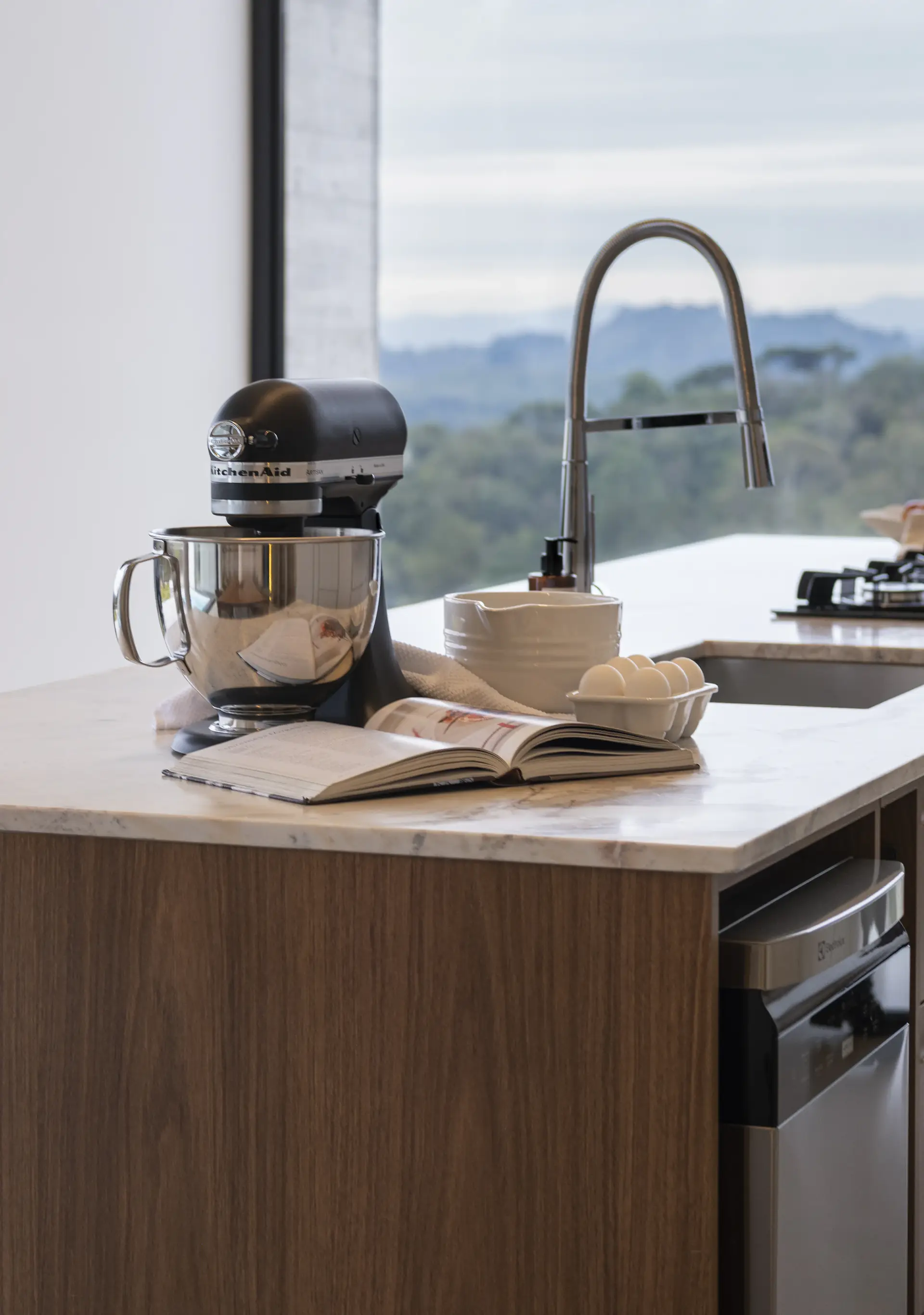 A stand mixer and open cookbook on a kitchen island