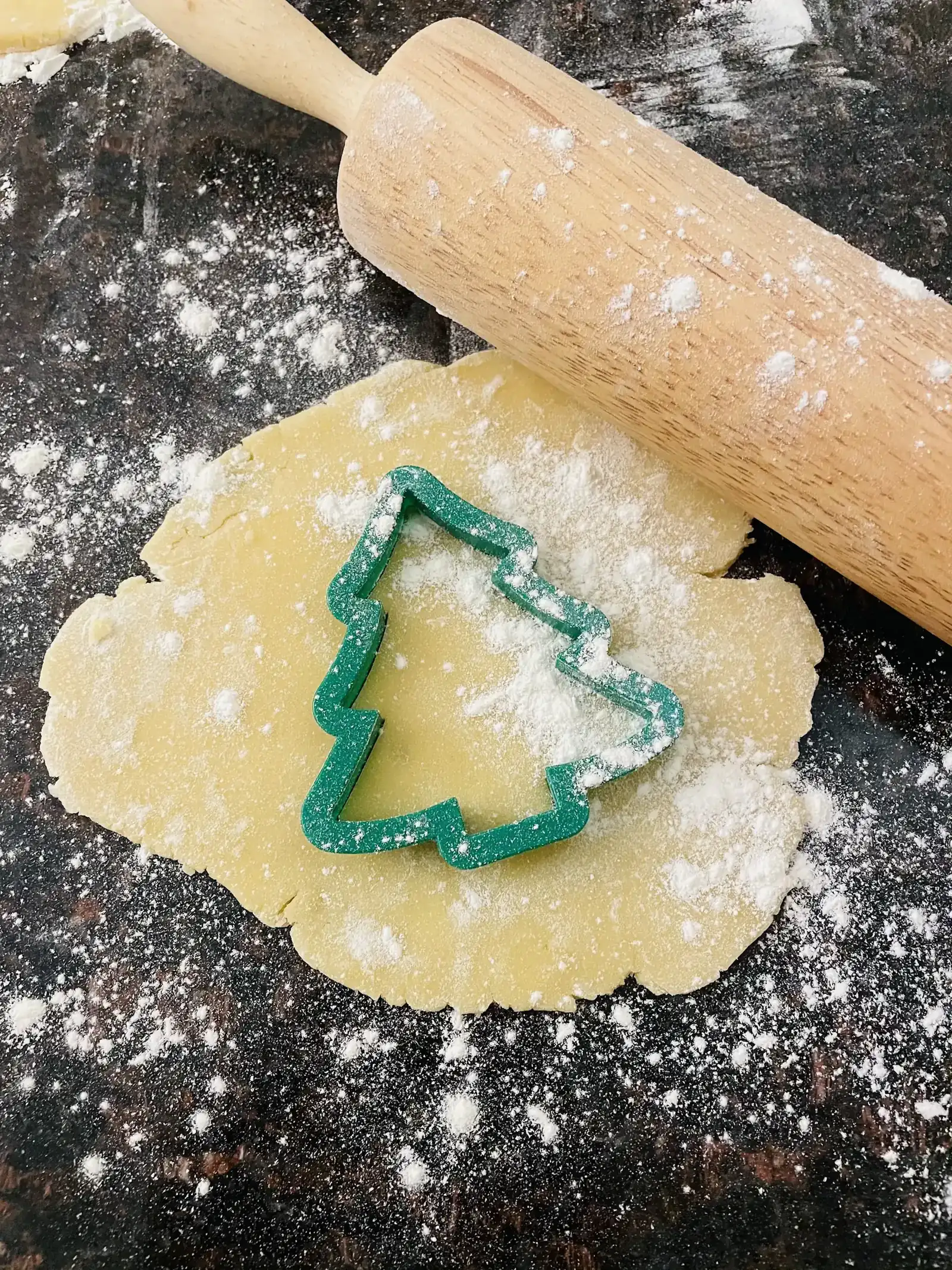 A Christmas tree cookie cutter on rolled dough