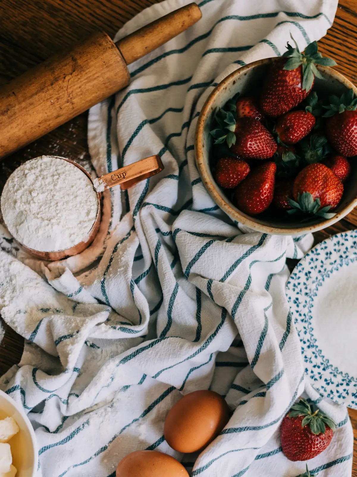 Strawberries, flour and eggs on a kitchen towel